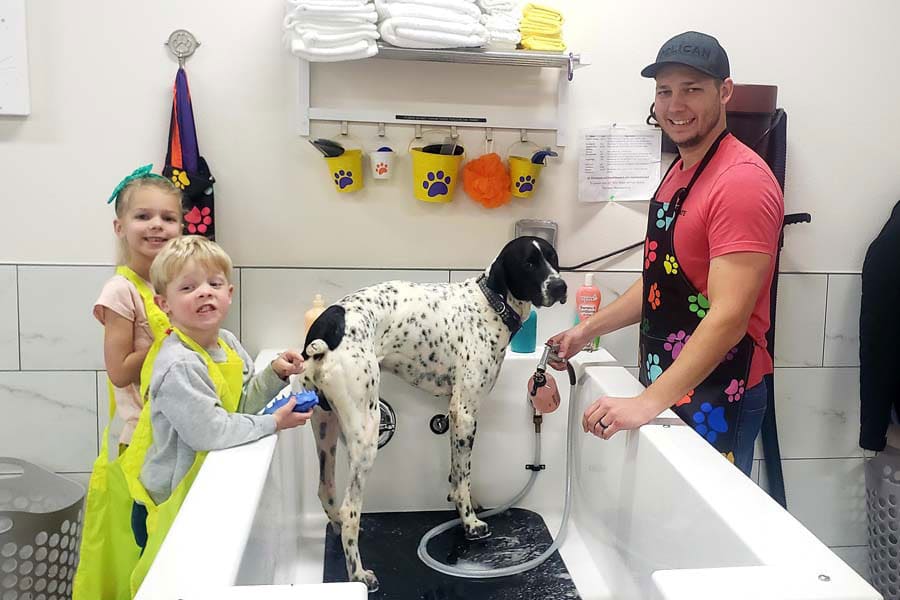 Family using self-service dog wash to wash family dog