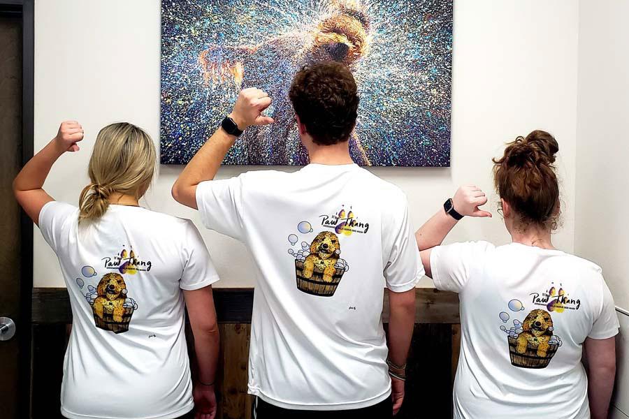 The backs of the staff wearing their "It's a Paw Thang" company t-shirts